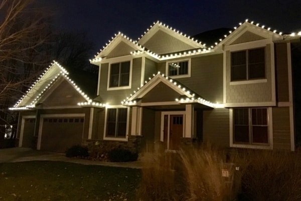 Festively decorated roofline with vibrant Christmas lights illuminating a house during the holiday season.
