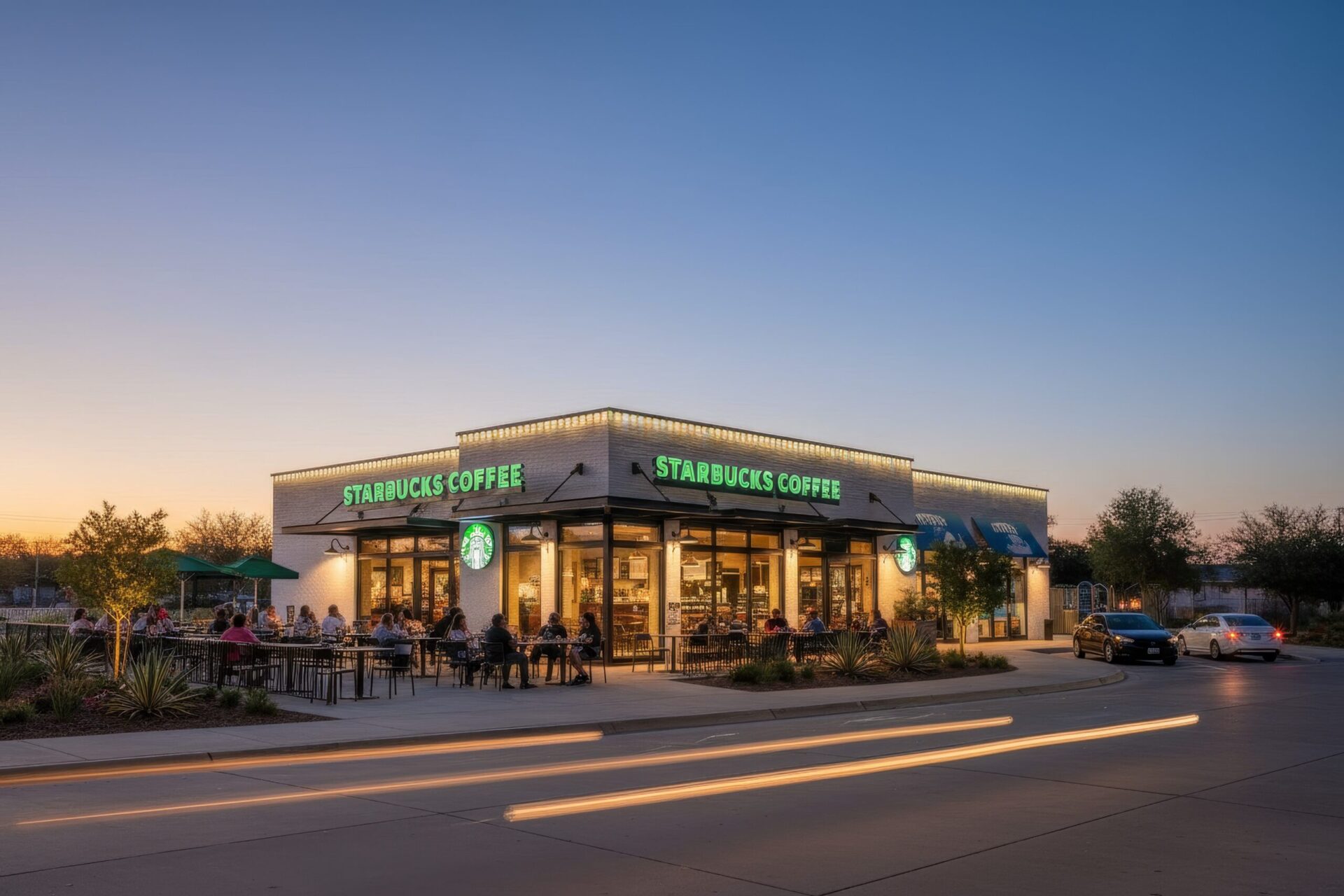 Starbucks drive-thru at dusk with warm white LED roofline lighting, showcasing cars in the drive-thru lane and a wide street view.