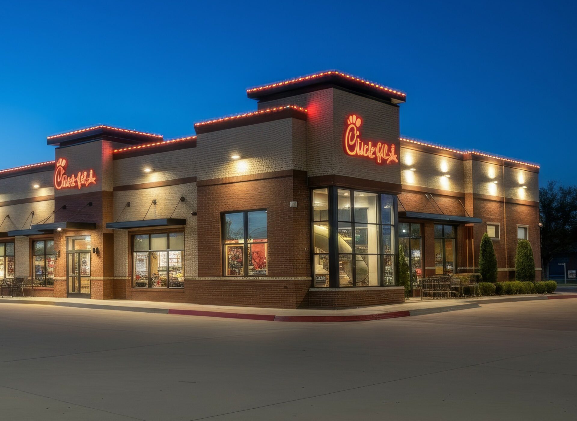 Chick-fil-A restaurant exterior with full parking lot, landscaping and warm LED roofline lighting at night